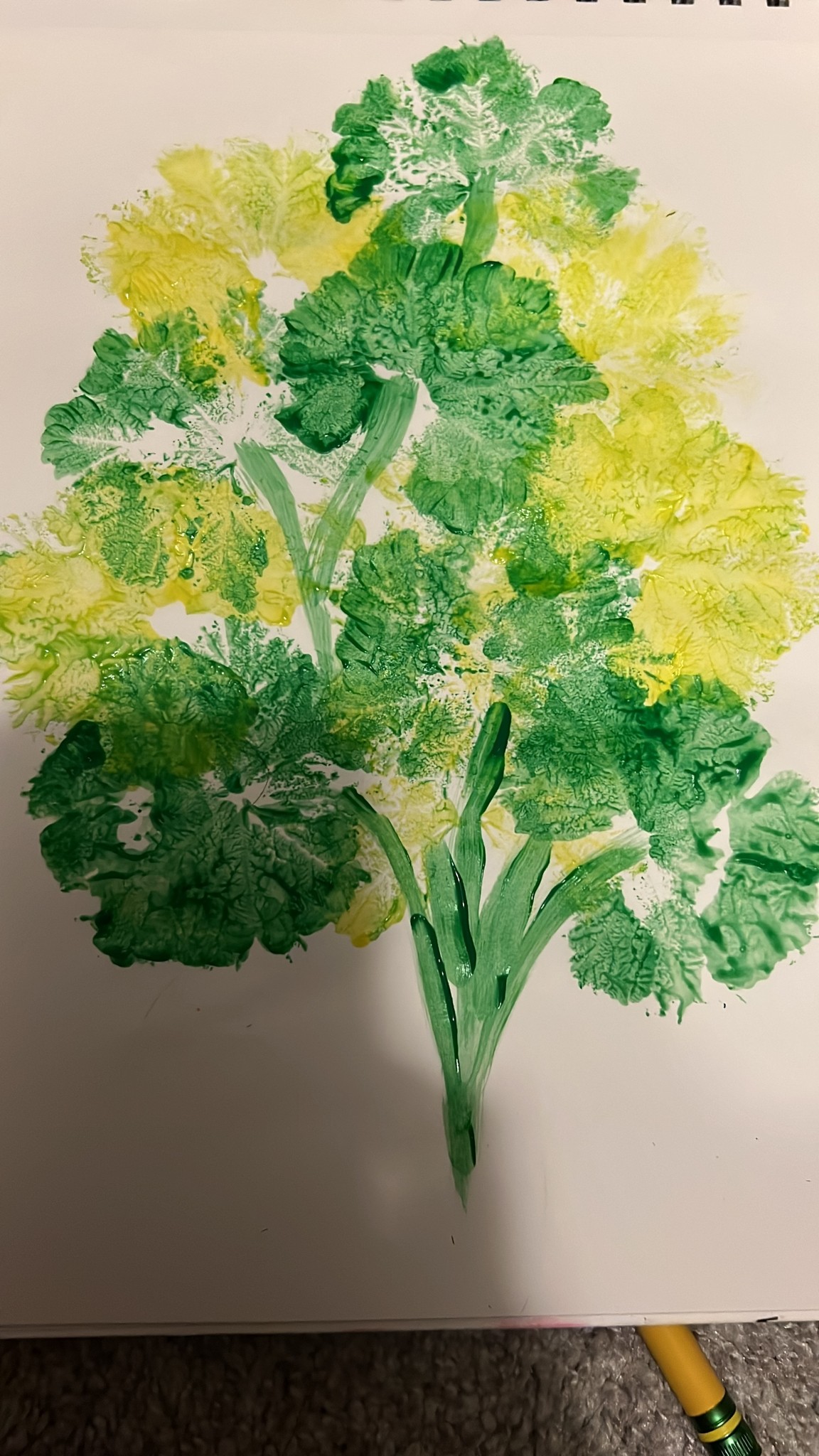 A branching arrangement of textured green and yellow foliage on white paper.