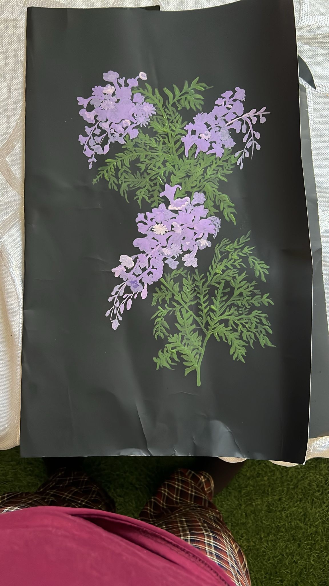 Small clusters of lilac flowers and fine green foliage painted on a black sheet.